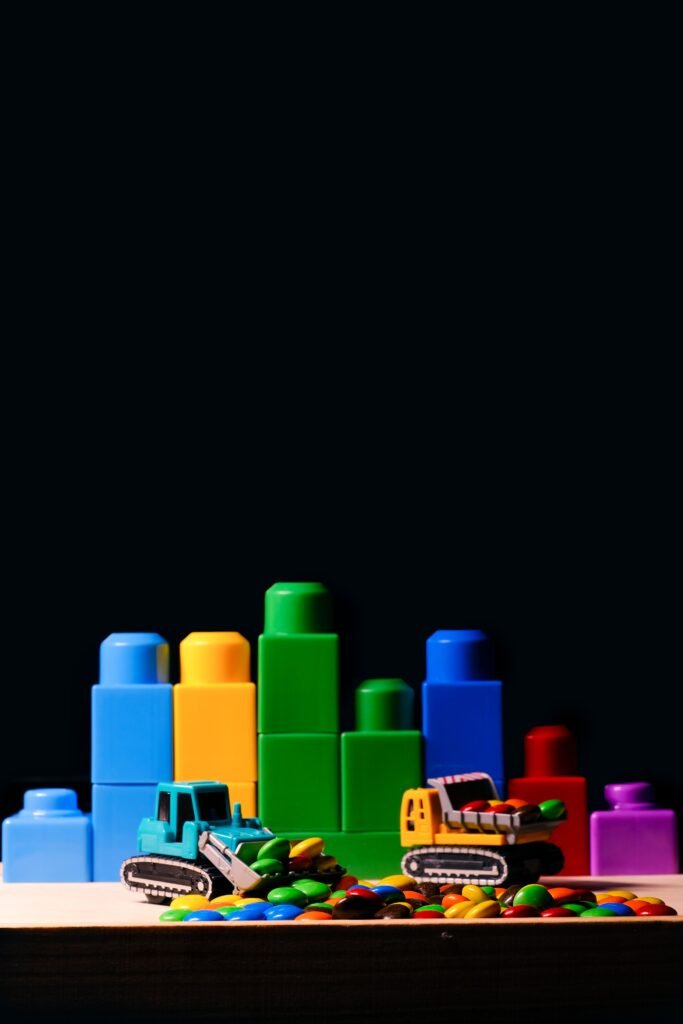 Vibrant toy blocks and bulldozers displayed on a wooden surface, against a black background.